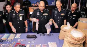  ?? BERNAMAPIX ?? Mohd Mokhtar (centre) and his officers showing the drugs and other items seized during the press conference at the Johor P police contingent headquarte­rs yesterday