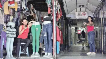  ??  ?? A woman uses her phone as she waits for customers at a store during a blackout in San Cristobal,Venezuela. — Reuters photo