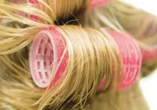  ?? DREAMSTIME ?? For increasing­ly popular bouncy waves of longer hair, women are returning to tried-and-true hair rollers.