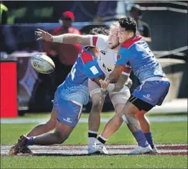  ?? Photograph­s by Gina Ferazzi Los Angeles Times ?? USA EAGLES’ Ben Pinkelman, center, gets a pass off just before being tackled by Samoa’s Laaloi Leilua, left, and Tomasi Alosio during a match Saturday.