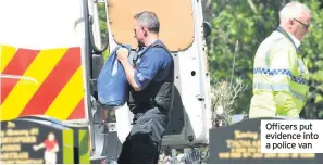  ??  ?? Officers put evidence into a police van