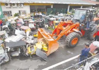  ??  ?? COLORUM – A payloader is used by the Quezon City Department of Public Order and Safety to crush and destroy illegally operating tricycles seized all over the city. A total of 38 tricycles were destroyed after a string of anti-colorum operations. (Mark...