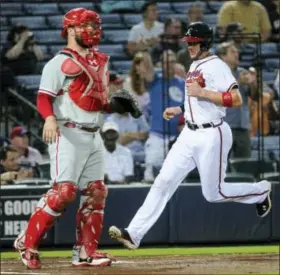  ?? JOHN AMIS — THE ASSOCIATED PRESS ?? Atlanta Braves’ Tyler Flowers scores on a line-drive triple to right field by Dansby Swanson as Phillies catcher Cameron Rupp looks on in the second innning Wednesday.