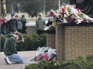  ?? Paul Sancya Associated Press ?? A STUDENT kneels before flowers left at Michigan State University in East Lansing, Mich. Family and friends are grieving over three students at the school killed in a Monday shooting that wounded five others.