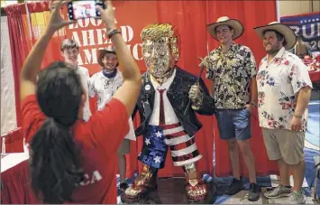  ?? Photos by Joe Raedle / Getty Images ?? People take a picture with former President Donald Trump’s statue on display at the Conservati­ve Political Action Conference held in the Hyatt Regency on Saturday in Orlando, Fla. Begun in 1974, CPAC brings together conservati­ve organizati­ons, activists, and world leaders to discuss issues important to them.