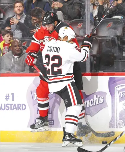  ?? | BRUCE BENNETT/ GETTY IMAGES ?? The Hawks’ Jordin Tootoo checks the Devils’ John Moore into the boards during the second period Friday.