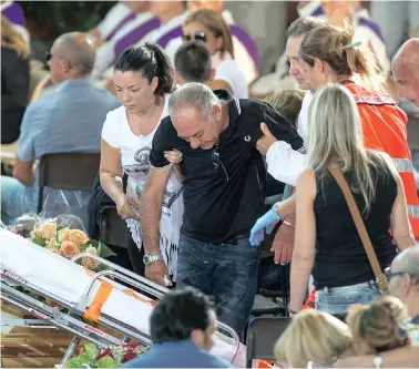  ?? PICTURE: REUTERS ?? DEVASTATED: A man is helped by Red Cross members during a funeral service for victims of the earthquake inside a gym in Ascoli Piceno, Italy, on Saturday.