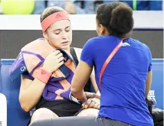  ?? — AFP photo ?? Ostapenko (left) receives treatment on her arm during her women’s singles second round match against Wang at the China Open tennis tournament in Beijing.