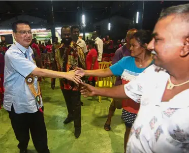  ??  ?? Sharing in the joy: (From left) Liow and Bentong Tamil Methodist Church Pastor Ezekiel Raj greeting visitors during Christmas celebratio­ns at Taman Karak.