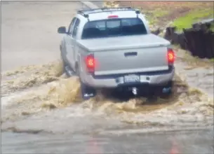  ?? Dan Watson/The Signal ?? A pickup truck with water up to its hubcaps crosses the Road as heavy rain falls in Santa Clarita on Thursday. swollen stream at Quigley Canyon