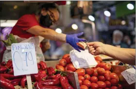  ?? ASSOCIATED PRESS FILE PHOTO ?? A customer pays for vegetables at the Maravillas market in Madrid.