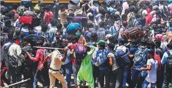  ?? AFP ?? A policeman disperses migrant workers gathered outside a railway station intending to board a special service train without valid tickets in Mumbai yesterday.