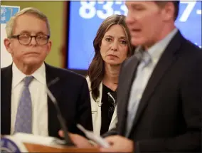  ?? DORAL CHENOWETH — THE COLUMBUS DISPATCH VIA AP ?? Ohio Department of Health director Dr. Amy Acton attends a news conference about the coronaviru­s March 16 at the Ohio Statehouse. She is framed between Ohio Gov. Mike DeWine and Lt. Gov. Jon Husted.