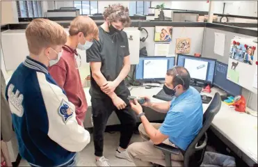  ?? Erin Gray Cantrell ?? Model High School students Jacob Jenkins (from left), Daniel Schabort and Patrick Clarke go over a 3D print of an extruding machine handle with Suhner Global Quality Manager Jon Baker.