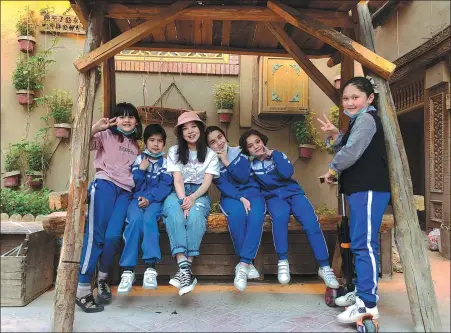  ?? PHOTOS PROVIDED TO CHINA DAILY ?? Above: Wang Wei (third from left), an entreprene­ur from Zhengzhou, Henan province, plays with local children at her guesthouse, Muse, in the Ancient City of Kashgar, a national 5A tourism attraction in the Xinjiang autonomous region.
Right: Fourth generation carpenter Husanjan Yusup (center) with his two sons in front of their woodworkin­g studio, also in Kashgar.
Below right: Wang helps her young neighbors with their homework at her guesthouse.
Bottom: Mardan Ablimit, a Kashgar native, makes coffee in his cafe.