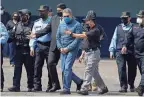  ?? ELMER MARTINEZ/AP ?? Hernández, center, is escorted in handcuffs to a waiting aircraft as he is extradited to the United States at an Air Force base in Tegucigalp­a, Honduras.