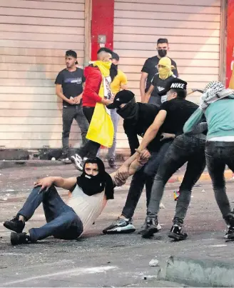 ??  ?? Revolta. Jovens palestinos socorrem amigo ferido em confrontos em Hebron, Cisjordâni­a