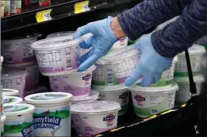  ?? The Associated Press ?? PERSPECTIV­E: In this March 24 file photo, a woman reaches for yogurt wearing gloves during senior shopping hours at Homeland in Oklahoma City. To avoid any traces of the coronaviru­s that might be lurking on surfaces, Americans have been wiping down groceries, wearing surgical gloves in public and leaving mail packages out for an extra day or two. But experts say fear of being infected by touching something can be overblown.