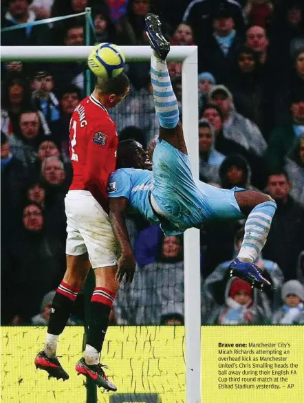  ??  ?? Brave one: Manchester City’s Micah Richards attempting an overhead kick as Manchester United’s Chris Smalling heads the ball away during their English FA Cup third round match at the Etihad Stadium yesterday. — AP