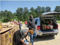  ?? Staff photo by Greg Bischof ?? ■ Volunteers for the Christian Food Pantry in Domino, Texas, load cars and trucks with food items late Thursday morning in an effort to help families who have been unable to return to work as a result of the continuing COVID-19 pandemic. The pantry has had as many as 340 families visit in one week.