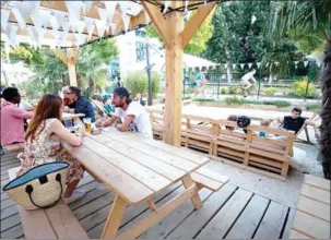  ?? THOMAS SAMSON/AFP ?? People enjoy a drink and have a chat at an open-air cafe (a in French) at the Grandes Serres de Pantin, a former industrial wasteland in Pantin, on the outskirts of Paris.