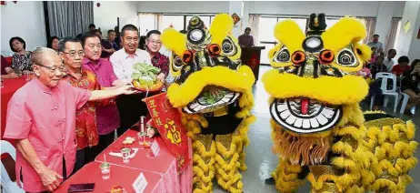  ??  ?? Season’s greetings: Ong (third from left) receiving a tray filled with items symbolisin­g good luck and fortune from lion dancers during the Hock Kean Kong Hoey open house in Ipoh.