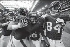  ?? TRIBUNE NEWS SERVICE ?? Houston Texans running back Lamar Miller (26) is congratula­ted by teammates after scoring a touchdown against the Oakland Raiders in last week's playoff game.