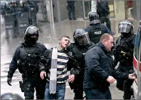  ?? AP/VISAR KRYEZIU ?? Kosovo police in riot gear detain a man during a raid Saturday at the opposition party headquarte­rs in Pristina.