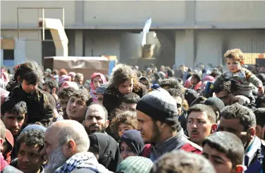  ?? SANA via AP ?? ■ This photo released by the Syrian official news agency SANA shows Syrian civilians with their belongings Friday as they flee from fighting between the Syrian government forces and rebels near Hamouria in eastern Ghouta, a suburb of Damascus, Syria....