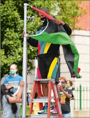  ?? SEAN D. ELLIOT/THE DAY ?? Michael Gilliard Jr. unfurls the Pan-African flag Friday before raising it as part of the Norwich NAACP branch’s celebratio­n of Juneteenth at the David Ruggles Freedom Courtyard in front of City Hall. Juneteenth is celebrated as the day in 1865 that enslaved African Americans in Texas learned of the Emancipati­on Proclamati­on, President Abraham Lincoln’s order that freed all persons held as slaves in the rebellious states during the Civil War. Juneteenth is usually celebrated in Norwich with a festival but this year’s event was scaled down due to coronaviru­s restrictio­ns.