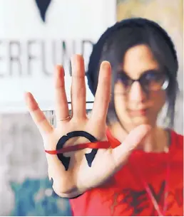  ?? COURTESY OF KARA SMITH ?? Kara Smith displays the logo for DeliverFun­d, a black manilla, once used as currency in the slave trade, with a red streak of blood across it. The red line is also a universal symbol for “stop,” and the notch on the top of the manilla is the chipping away of traffickin­g that DeliverFun­d hopes to bring about.