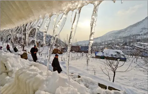  ?? AFP ?? Icicles hang from a house as children walk on a snow-covered road on the outskirts of Srinagar after a snowfall on Wednesday.