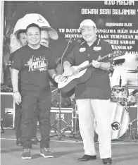  ??  ?? HAJIJI bermain gitar sebagai gimik perasmian Battle of the Bands, diperhatik­an oleh Jasni.