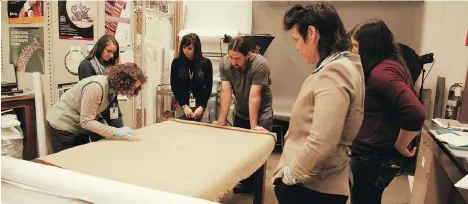  ?? BURKE MUSEUM ?? Burke Museum researcher­s study a Coast Salish blanket that was recently found to contain hair from the extinct woolly dog.