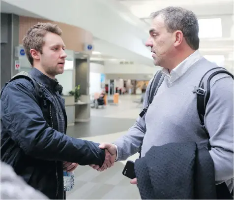 ?? PHOTOS: LEAH HENNEL ?? Rock Ruschkowsk­i, left, who was traded halfway through the Humboldt Broncos season, arrives at the Saskatoon Airport on Sunday and is greeted by Bob Wilkie, who survived the fatal bus crash involving the Swift Current Broncos in 1986.