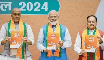  ?? — Reuters ?? Indian Defence Minister Rajnath Singh, PM Narendra Modi and President of the Bharatiya Janata Party J. P. Nadda display copies of the ruling Bharatiya Janata Party’s (BJP) election manifesto for the general election, in New Delhi.
