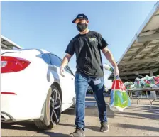  ?? PHOTO VINCENT OSUNA ?? Imperial County Office of Education’s Joel Flores places an “Essential Bag” into a guest’s vehicle during ICOE’s distributi­on event on Thursday in El Centro.