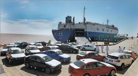  ?? FANG ZHE / XINHUA ?? Automobile­s are unloaded from a cargo carrier at a port in Lingang in Pudong New Area, Shanghai.