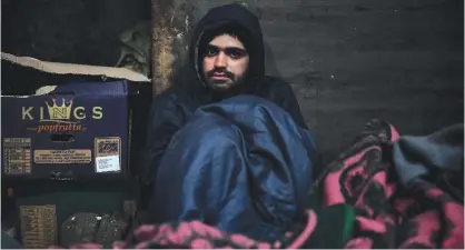  ?? — AFP ?? BELGRADE: Mohamed Darwich, a 17-year old migrant from Afghanista­n, poses in a makeshift shelter at an abandoned warehouse.