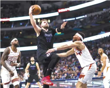  ?? PRESSE AGENCE FRANCE ?? Luka Doncic #77 of the Dallas Mavericks drives inside for a shot against Devin Booker #1 of the Phoenix Suns in the second half at American Airlines Center in Dallas, Texas.