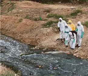  ?? PIC BY ADI SAFRI ?? The Fire and Rescue Department hazardous materials (Hazmat) team cleaning up the chemically-polluted Sungai Kim Kim in Pasir Gudang, Johor, recently.