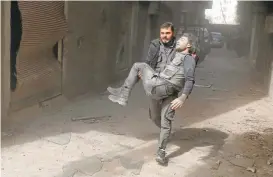  ?? ABDULMONAM EASSA/AGENCE FRANCE-PRESSE VIA GETTY IMAGES ?? A wounded Syrian civil defense volunteer evacuates his injured colleague following a reported airstrike Saturday on the rebel-controlled town of Hamouriyeh.