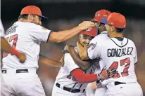  ?? NICK WASS/THE ASSOCIATED PRESS ?? The Nationals’ Tanner Roark, left, and Gio Gonzalez, right, mob Ryan Raburn, center, after he hit a walk-off single to score Matt Wieters in the bottom of the ninth inning Monday against the Mets in Washington.