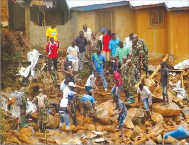  ?? Associated Press photo ?? Volunteers search for bodies from the scene of heavy flooding and mudslides in Regent, just outside of Sierra Leone’s capital Freetown. Tuesday.