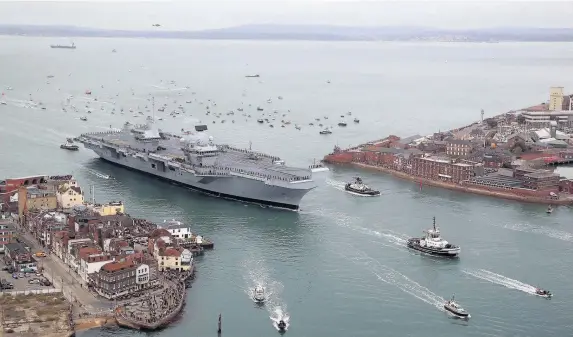  ??  ?? > HMS Queen Elizabeth, the UK’s newest aircraft carrier, arrives in Portsmouth. The 65,000-tonne carrier is the largest warship ever to be built in Britain