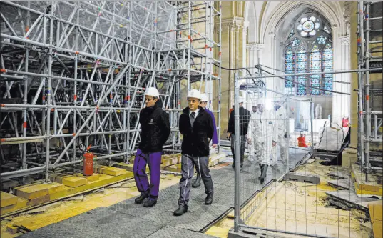  ?? Sarah Meyssonnie­r The Associated Press ?? French President Emmanuel Macron, center, tours Notre Dame Cathedral in Paris on Friday, marking the one-year countdown to its scheduled reopening on Dec. 8, 2024, after a massive fire tore through the treasured landmark on April 15, 2019.