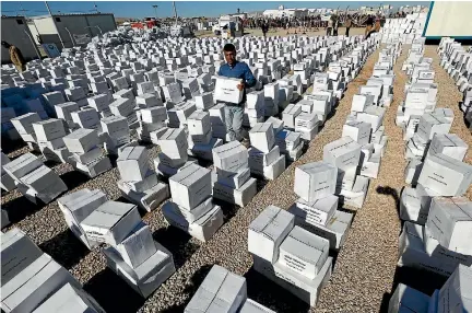  ?? PHOTO: REUTERS ?? A worker carries a box as displaced Iraqis who fled the Islamic State stronghold of Mosul wait to receive humanitari­an aid supplies at Hassan Sham camp, east of Mosul, Iraq.