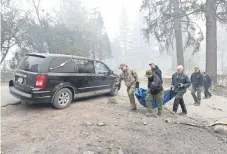  ??  ?? Autoridade­s cargan un cuerpo a una carroza, tras haberlo sacado ayer de una vivienda quemada en Paradise, California.