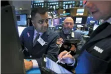  ?? RICHARD DREW — THE ASSOCIATED PRESS FILE ?? Specialist Dilip Patel, left, works at his post on the floor of the New York Stock Exchange.