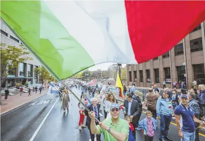  ?? STAFF PHOTOS, LEFT, BY NANCY LANE; ABOVE, BY NICOLAUS CZARNECKI ?? RED, WHITE AND GREEN GALORE: Two-year-old Isaiah Burghgraef, at left, gets in the Italian spirit waving a flag at the Columbus Day Parade in Boston yesterday. A marcher, above, waves an Italian flag as a group walks during the parade.